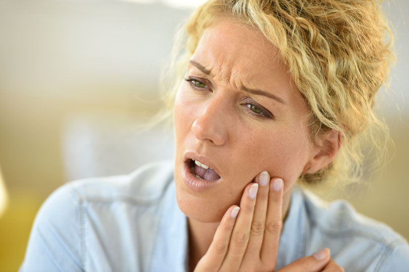 Woman touching her hurting cheeks and thinking about Emergency Dentist Stoney Creek