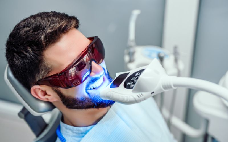 dentist starting teeth whitening procedure young